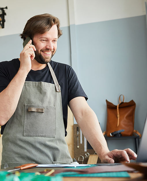 Young man with an apron talking on the phone